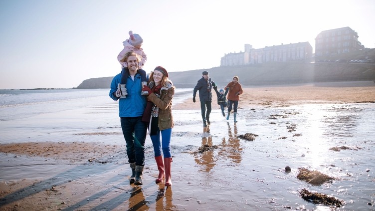 Family walking towards the camera on the beach in the winter sunshine, Tynemouth, Northumberland